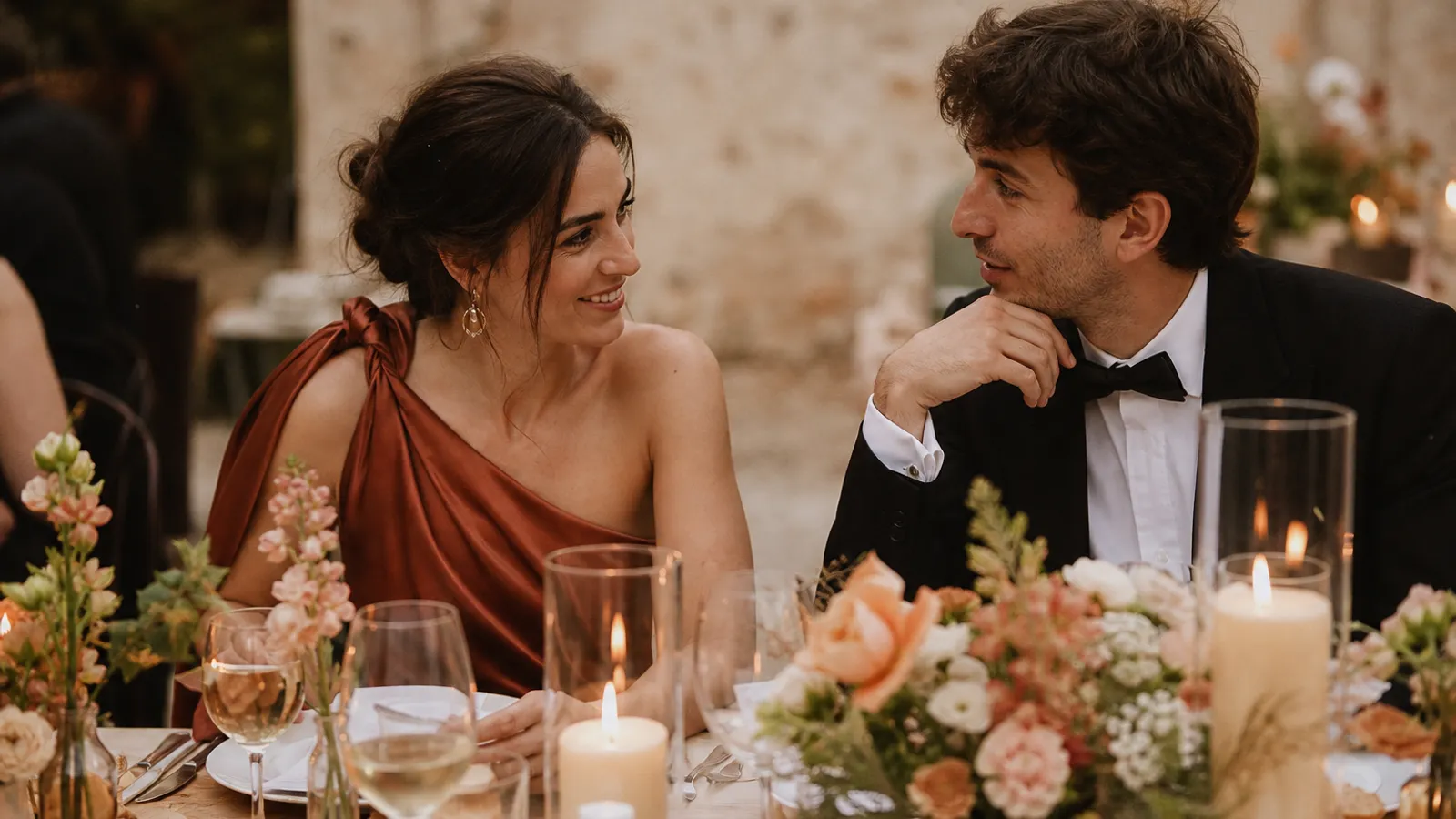 Zwei Gaeste an einem festlich gedeckten Hochzeitstisch im Gespraech
