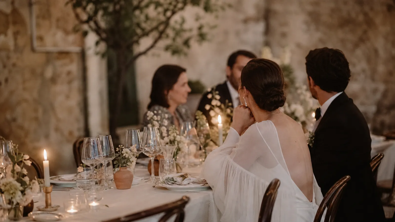 An elegant evening wedding reception table set for adults, softly lit