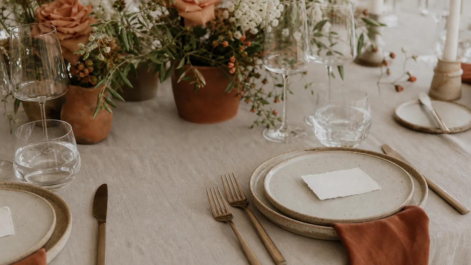 Two place settings at a wedding table, one with a name card and one blank